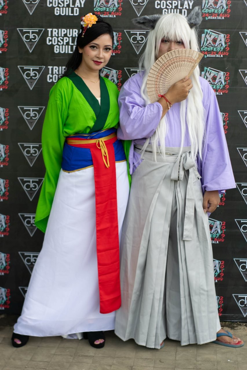 Two cosplayers posing together in front of the Tripura Cosplay Guild backdrop